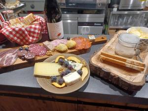 Chambres d hôtes Le clos des vins d anges في Saint-Pierre-des-Champs: طاولة مع صحن من الجبن وزجاجة من النبيذ