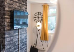 a room with a clock and a tv on a wall at Coventry Michaelmas Pet Friendly 2 Bedroom Apartment in Parkside