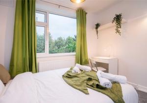 a bedroom with a bed with green curtains and a window at Coventry Michaelmas Pet Friendly 2 Bedroom Apartment in Parkside