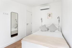 a white bedroom with a bed and a mirror at Lapa Duplex Apartment in Lisbon
