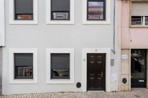 a white building with black doors and windows at Lapa Duplex Apartment in Lisbon