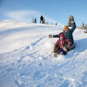 duas pessoas estão sentadas na neve num snowboard em Yellowknife Downtown 50a avenue Retreat em Yellowknife