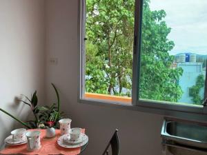 een tafel met bekers en schotels en een raam bij Phuket Latika Mansion by Andaman Home in Phuket