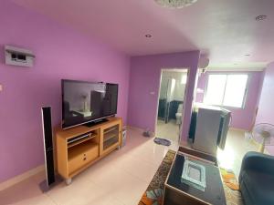 a living room with a tv and a purple wall at Phuket Latika Mansion by Andaman Home in Phuket Town