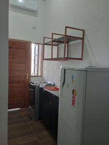 a kitchen with a white refrigerator and a sink at Cantinho do Sossego - kitnets in Cananéia