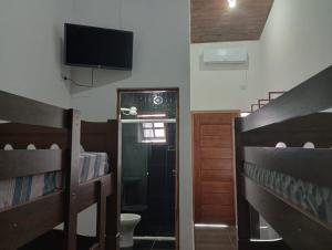 a room with two bunk beds and a flat screen tv at Cantinho do Sossego - kitnets in Cananéia