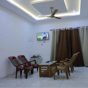 a living room with chairs and a table and a ceiling at LOVESHORE Homestay in Kollam