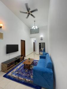 three bedroom tarraced house - RainaHomestay Pasir Gudang في باسير غونداغ: غرفة معيشة مع أريكة زرقاء وتلفزيون