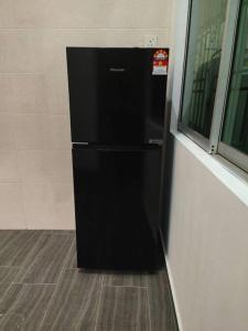 a black refrigerator in the corner of a room at three bedroom tarraced house - RainaHomestay Pasir Gudang in Pasir Gudang