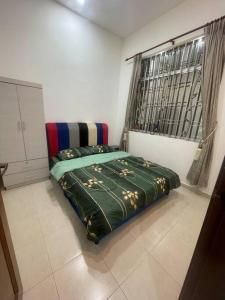 three bedroom tarraced house - RainaHomestay Pasir Gudang في باسير غونداغ: غرفة نوم مع سرير مع لحاف أخضر ونافذة