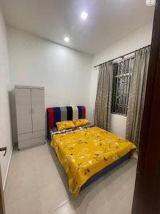three bedroom tarraced house - RainaHomestay Pasir Gudang في باسير غونداغ: غرفة نوم بسرير وبطانية صفراء