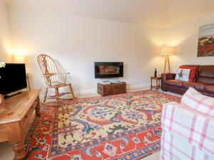 a living room with a couch and a tv at Wellington Lodge Cottage in Richmond