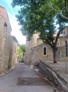 naast een stenen gebouw staat een boom bij Chambre d'hôte Au Jardin Le clos des vins d'Anges in Saint-Pierre-des-Champs