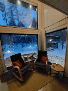 2 stoelen en een tafel in een kamer met ramen bij SHANTI FOREST HOUSE Guest house with mirror sauna 