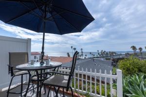 un tavolo e delle sedie su un balcone con un ombrellone di Panoramic Ocean View Cottage and Hideaway Unit #4 and B a San Clemente