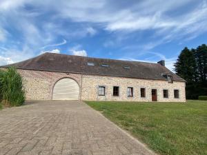 a large brick building with a garage at La demoiselle ô bois - Gite rural Chimay in Seloignes