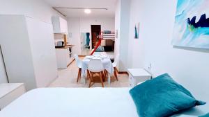 1 dormitorio con 1 cama blanca, mesa y sillas en Hostal Estudios, en Badalona