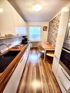 cocina con armarios blancos y mesa de madera en Ida, the suburban apartment nearby Cologne, en Bergheim