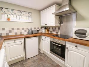 kuchnia z białymi szafkami i kuchenką mikrofalową w obiekcie 5 Gwynant Street w mieście Caernarfon