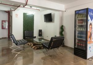 een wachtkamer met 2 stoelen en een drankkoeler bij Hotel Precursores in Lima