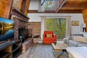 uma sala de estar com uma lareira de tijolos e uma televisão em Alta Vista Haus in Moonridge em Big Bear Lake
