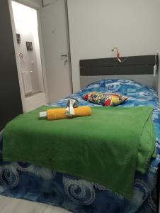 ein Bett mit einer grünen Bettdecke und einem Spielzeug darauf in der Unterkunft Sun shine in Cesano Boscone