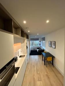 a kitchen with a table and a living room at LUXX Apartment & Suites, London Heathrow Airport, Terminal 4, Piccadilly underground Train station nearby! in New Bedfont