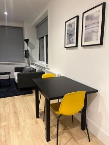 a living room with a black table and yellow chairs at LUXX Apartment & Suites, London Heathrow Airport, Terminal 4, Piccadilly underground Train station nearby! in New Bedfont
