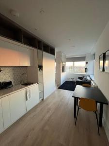 uma sala de estar com uma mesa e uma cozinha em LUXX Apartment & Suites, London Heathrow Airport, Terminal 4, Piccadilly underground Train station nearby! em New Bedfont