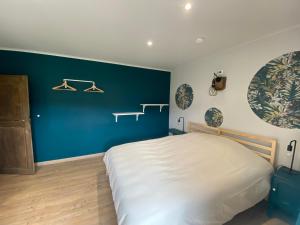 a bedroom with a bed and a blue wall at La demoiselle ô bois - Gite rural Chimay in Seloignes
