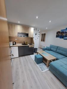 sala de estar con sofá azul y cocina en Apartmani Strahinja Jahorina, en Jahorina