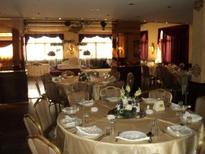 ein Festsaal mit Tischen und Stühlen mit weißen Tischdecken in der Unterkunft Platinum Hotel in Tyros