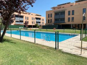 uma cerca em torno de uma piscina em frente a um edifício em Lujoso Apartamento 3 Camas Piscina Parque Garaje Las Rozas Familiar Tranquilo em Las Rozas de Madrid