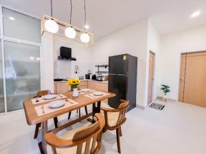 uma cozinha com uma mesa e cadeiras e um frigorífico preto em The Teak Poolvilla em Sattahip
