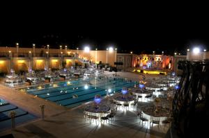 ein Pool mit Tischen und Stühlen bei Nacht in der Unterkunft Platinum Hotel in Tyros