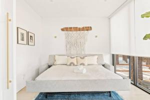 a white bedroom with a bed with a chandelier at Mountain Top Modern Lakefront in Sunset Magazine in Big Bear Lake +45 photos