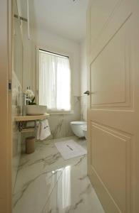 baño blanco con aseo y ventana en Liberty Dream, fascino a Vicenza, en Vicenza