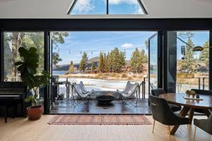 a living room with a large window and a table and chairs at Mountain Top Modern Lakefront in Sunset Magazine in Big Bear Lake