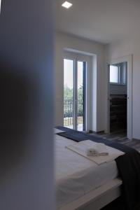 a white bedroom with a bed and a large window at Essentia Rooms & Relax in Vasto