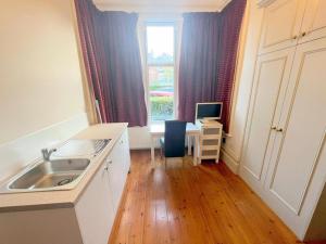 a kitchen with a sink and a desk with a computer at Sutton Studio Apartments in Cheam