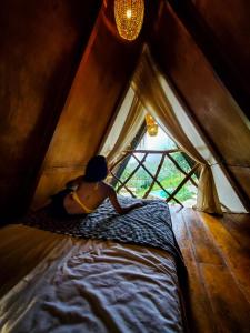 Una donna sdraiata su un letto in una tenda di Dream Ville a Ella