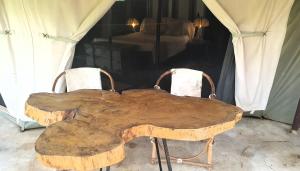 a wooden table with two chairs around it at Family Tent - Dolly Farm & River Camp in Usa River