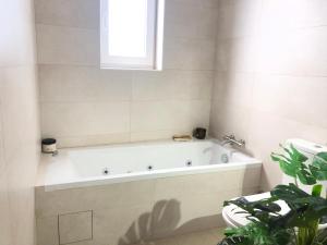 a white bath tub in a bathroom with a plant at Villa familiar com piscina e jacuzzi a 30 min de Lisboa in Torres Vedras