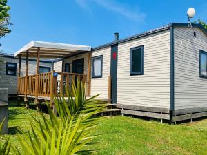 a mobile home with a porch and a deck at Camping La Sinope in Quinéville