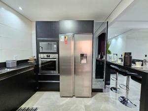 a stainless steel refrigerator in a kitchen with black cabinets at Sofisticado APT ao lado do Paraguai 3 quartos in Foz do Iguaçu