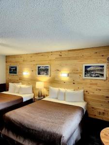 two beds in a hotel room with wooden walls at Rundle Mountain Lodge in Canmore