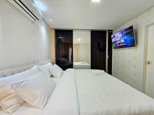a white bed with white pillows in a room at Sofisticado APT ao lado do Paraguai 3 quartos in Foz do Iguaçu