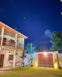 a white house with a gate and a garage at night at CASA CAMINHO do MAR in Pôrto de Pedras +29 photos
