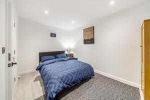 a bedroom with a bed with a blue comforter at Two Bed Home In the Heart of Egham in Egham