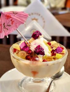 a bowl of fruit and ice cream with an umbrella at Grand River View Hotel - Rajshahi in Rājshāhi